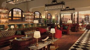 Een ruime lobby met een bar, leren banken en een geruite vloer.