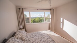 A bedroom with a bed, a window with curtains, and a view of greenery outside. - Amazing View, Walk to lake, very Central, borders state park. NEWLY RENOVATED! (Waterbury Center)