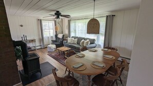 A cozy living room with a wooden dining table, a gray sofa, and a ceiling fan. - Amazing View, Walk to lake, very Central, borders state park. NEWLY RENOVATED! (Waterbury Center)