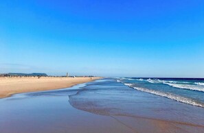 A wide beach with gentle waves and a clear sky.