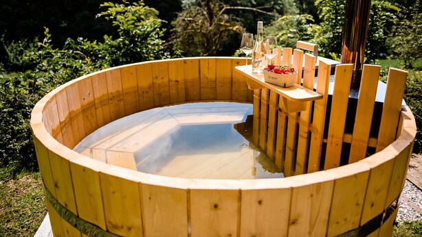 Eine Holzafütte Holztonne mit einer Sitzbank und einem Tisch mit Gläsern und Erdbeeren.