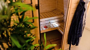 Eine Sauna mit Holzwänden und einer Sitzbank. Ein Handtuch hängt an der Wand und eine Flasche steht auf der Bank.