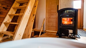 Ein Holzinnenraum mit Kaminofen und einer Holzleiter.