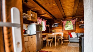 Ein gemütliches Blockhaus mit Holzwänden, einer Küchenzeile, einem Esstisch und einer Sitzecke mit einer Couch.