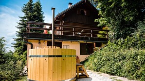 Eine Holzhütte mit Balkon, einem Holz-Whirlpool und einer Treppe zum Obergeschoss.