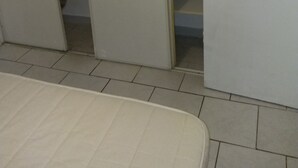 Ett rum med en säng, en garderob med skjutdörr och ett klinkergolv.