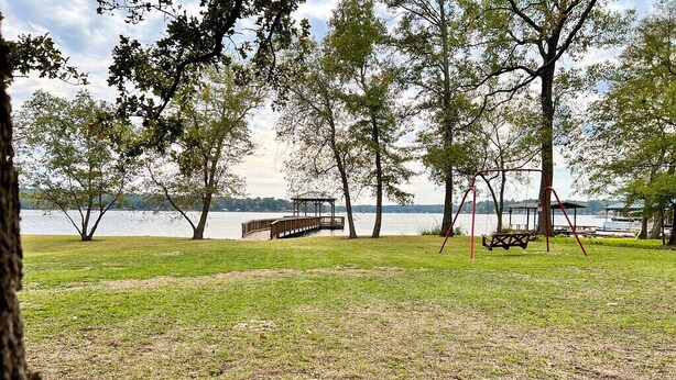 Ein Park mit einer Schaukel, Picknicktischen und einer Holzterrasse über dem Wasser.