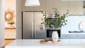 Une cuisine moderne dotée d’appareils électroménagers en acier inoxydable, d’un îlot central blanc et d’une plante décorative.