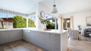 Une cuisine moderne dotée d’un grand îlot central, de meubles de rangement gris et offrant une vue sur l’extérieur.