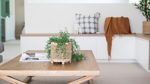 Une table en bois sur laquelle repose un panier tressé contenant des plantes vertes, un magazine et un stylo.
