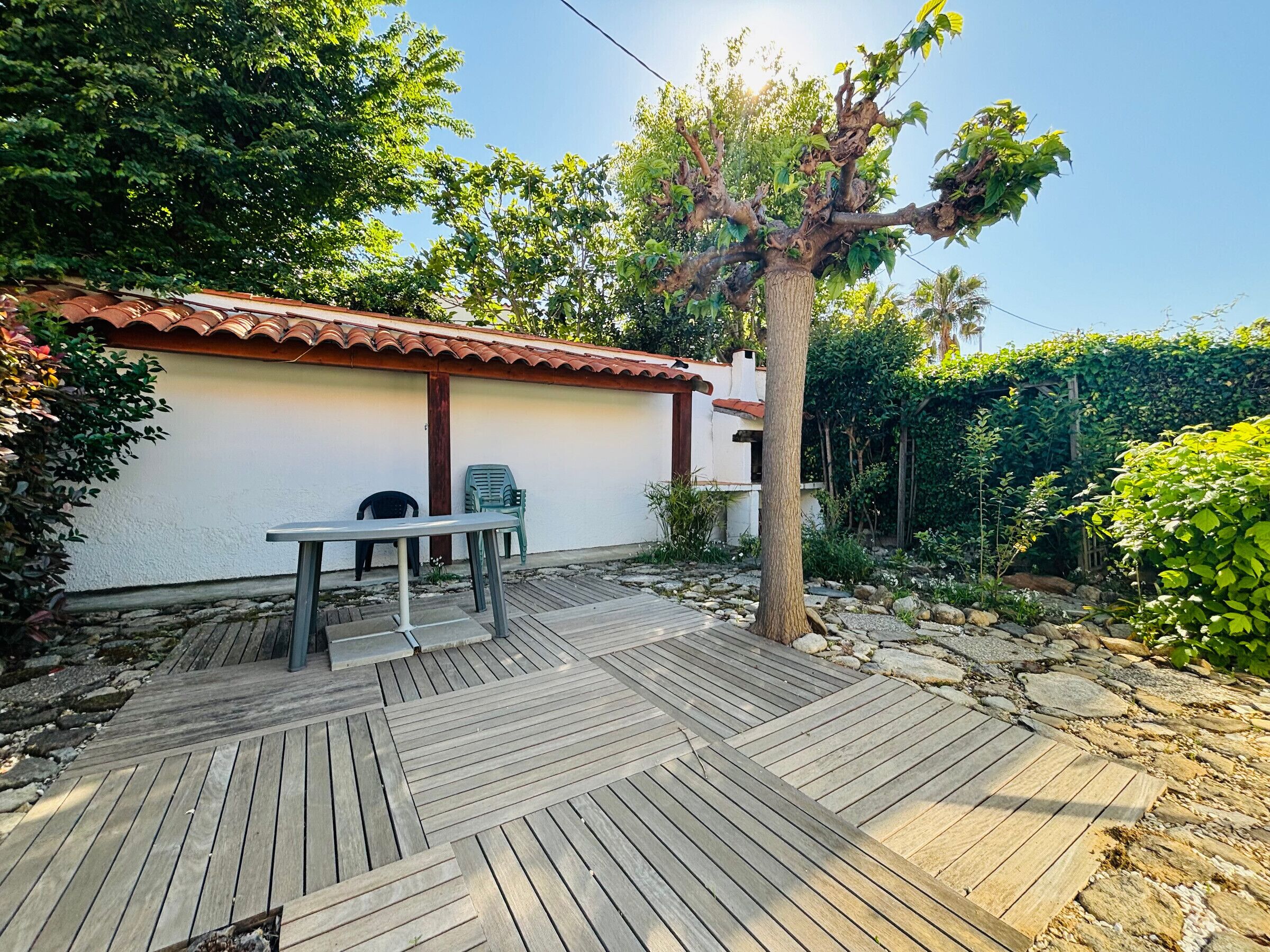 A patio area with a wooden deck, a table, and two chairs.