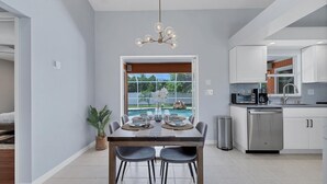 Una cocina moderna con armarios blancos, lavavajillas de acero inoxidable y horno empotrado.