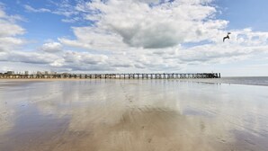 A beach with a pier extending into the water, sandy shore, and a partly cloudy sky. - 3-bedroom apartment with large balcony and garage near the casino (Saint-Jean-de-Monts)