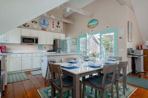 A kitchen with white cabinets, a microwave, and a dining area with a table set for four.