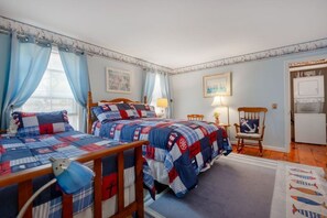 A bedroom with two beds, a chair, a lamp, and a fish-patterned rug.