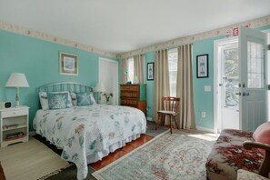 A bedroom with a bed, a dresser, a chair, and a door.