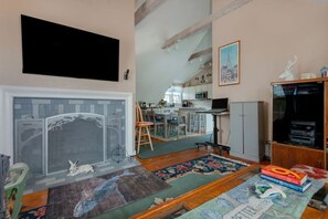 Una sala de estar con chimenea, televisión y estantería.