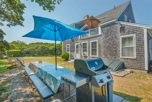 A backyard with a grill, picnic table, and umbrella.