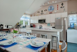 A kitchen with white cabinets, a stainless steel refrigerator, and a dining area set for four with a table and four chairs. - Nantucket Salty Nest- 3 bedroom 2.5 bathrooms in Tom Nevers. Sleep 7 (Nantucket)