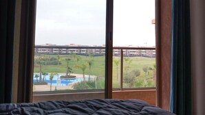 A room with a bed and a large window offering a view of a golf course and buildings. - PRESTIGIA GOLF CITY MARRAKECH (Marrakech)