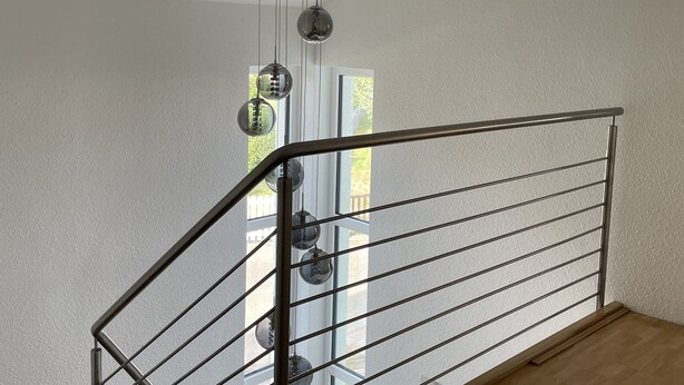 A modern staircase with a metal railing and a hanging spherical light fixture. - Modern "industrial style" vacation apartment with terrace + nearby playground (Parthenstein)