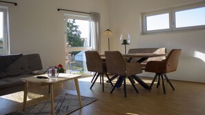 A modern living room with a sofa, a coffee table, and a dining area with chairs and a table. - Modern "industrial style" vacation apartment with terrace + nearby playground (Parthenstein)
