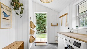 Een moderne keuken met witte kasten, een ingebouwde wasmachine en een houten bankje.