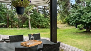 Een terras buiten met een tafel gedekt voor twee personen, omringd door rieten stoelen.
