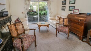 Una sala de estar con un sofá, dos sillones, una mesita de centro y un aparador de madera.