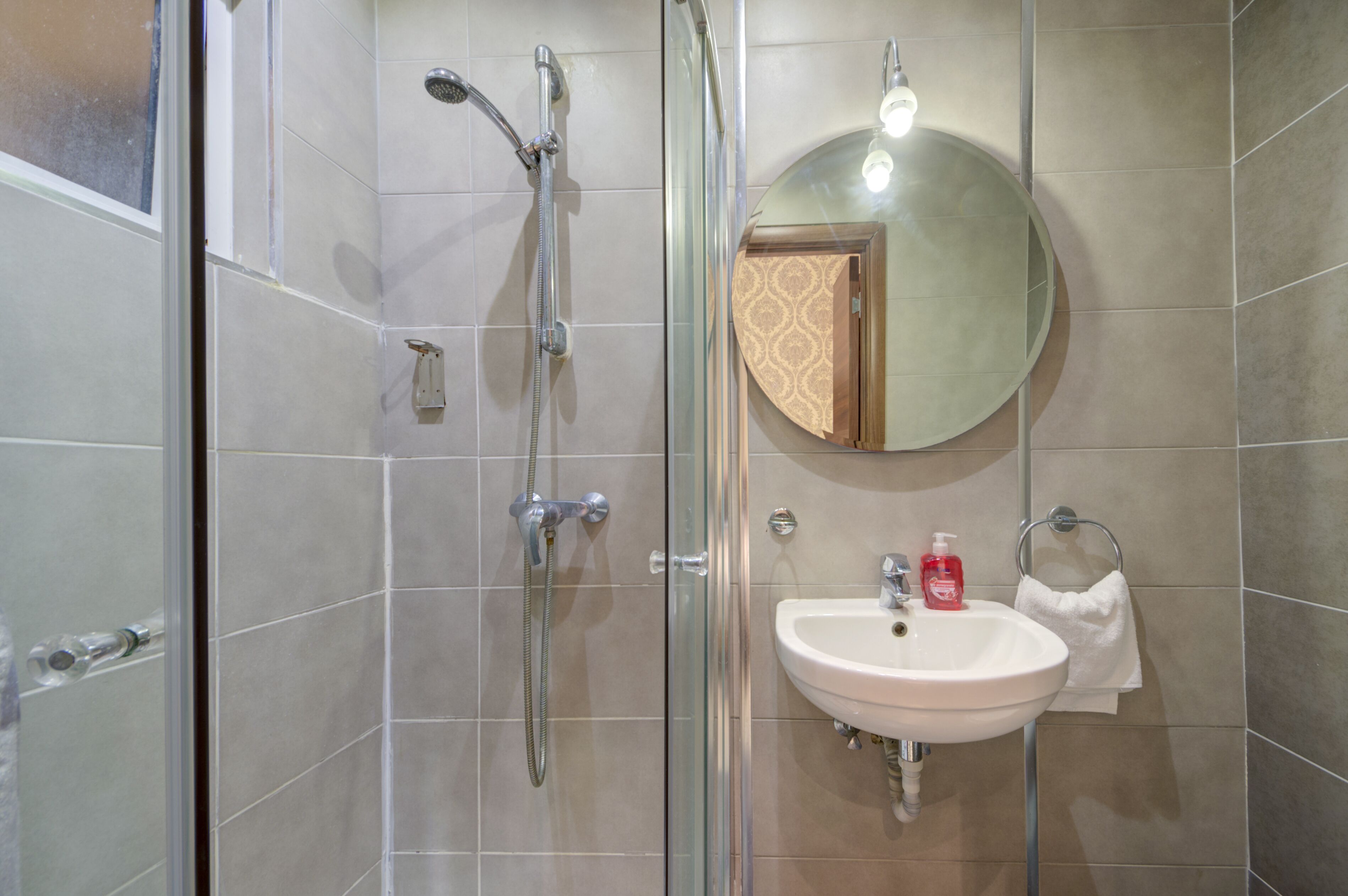 A bathroom with a glass shower enclosure, a sink, and a mirror.