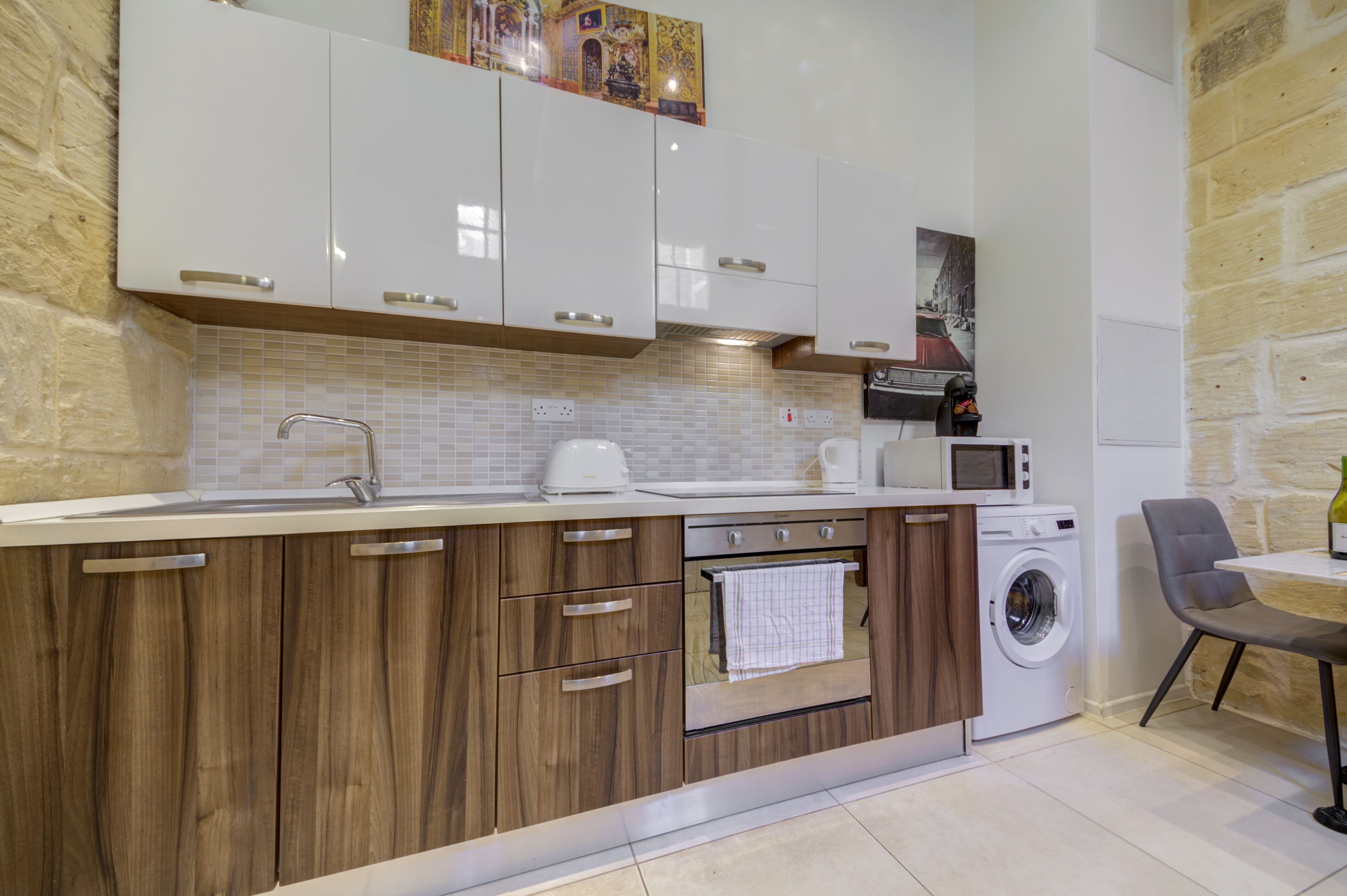 A modern kitchen with wooden cabinets, a built-in oven, a microwave, and a washing machine.