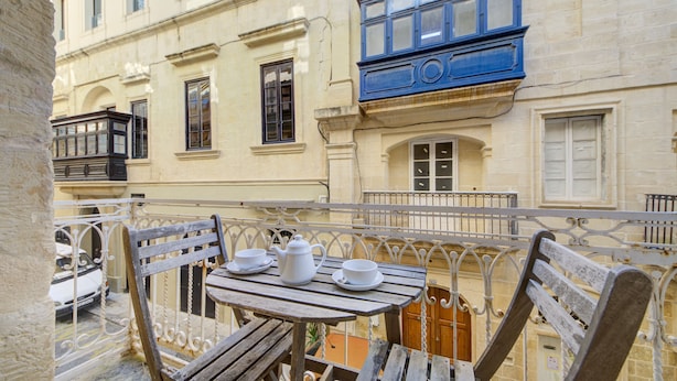 A balcony with a wooden table, two white cups, and a white teapot. - Tritoni harbour suites (Valletta)