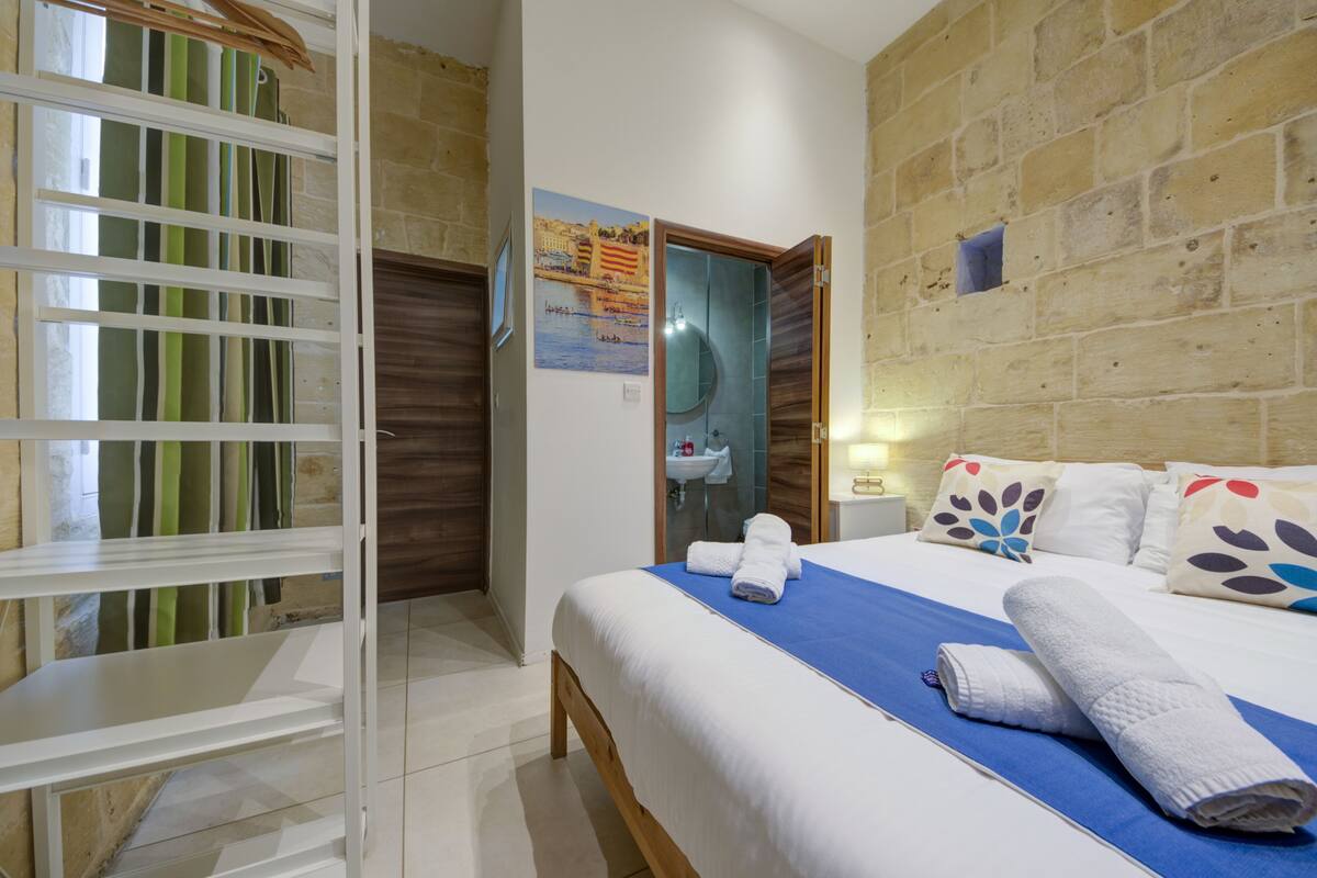 A hotel room with a bed, a bathroom, and a view of the outside.