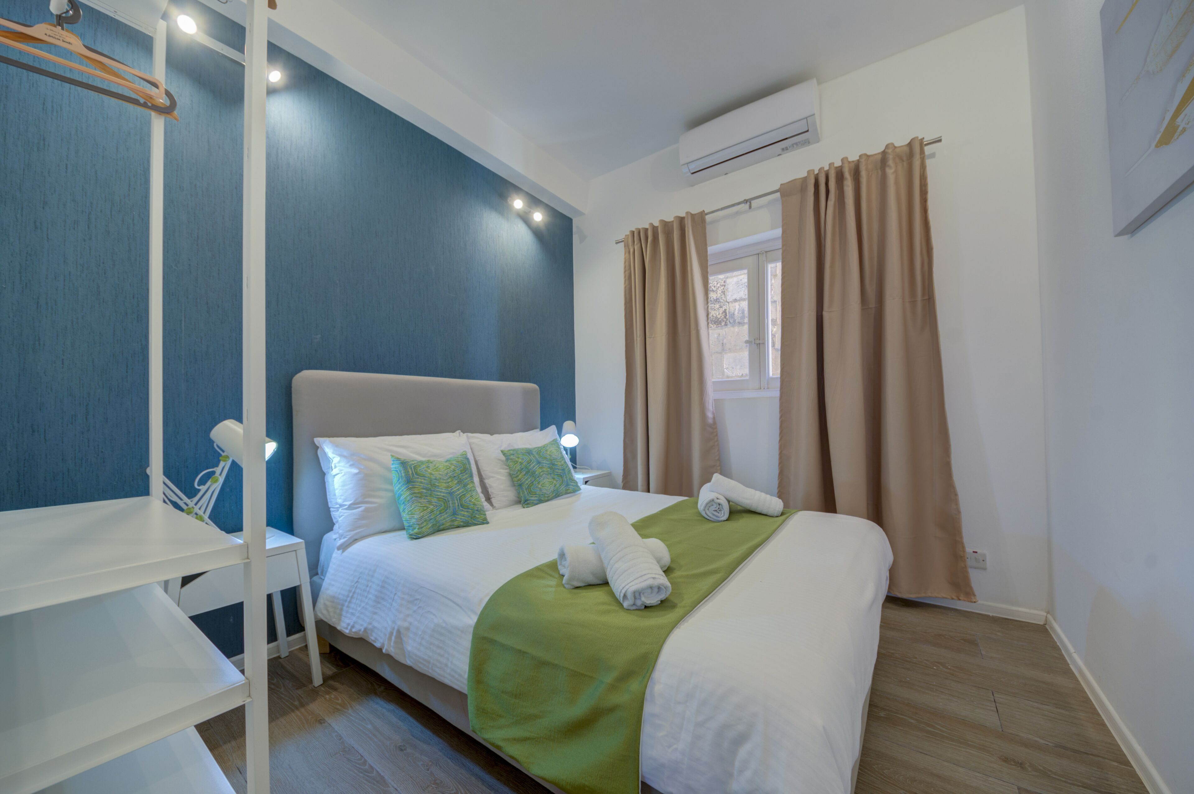 A neatly arranged bedroom with a bed, a bedside table, a chair, and a window with curtains.