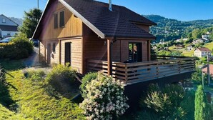 A wooden cabin with a sloped roof, a chimney, and a deck. - Casa de Monzel - Jacuzzi and panoramic view of the Bresse mountains (La Bresse)