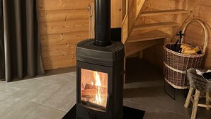 A wood-burning stove in a room with wooden walls and a staircase. - Casa de Monzel - Jacuzzi and panoramic view of the Bresse mountains (La Bresse)