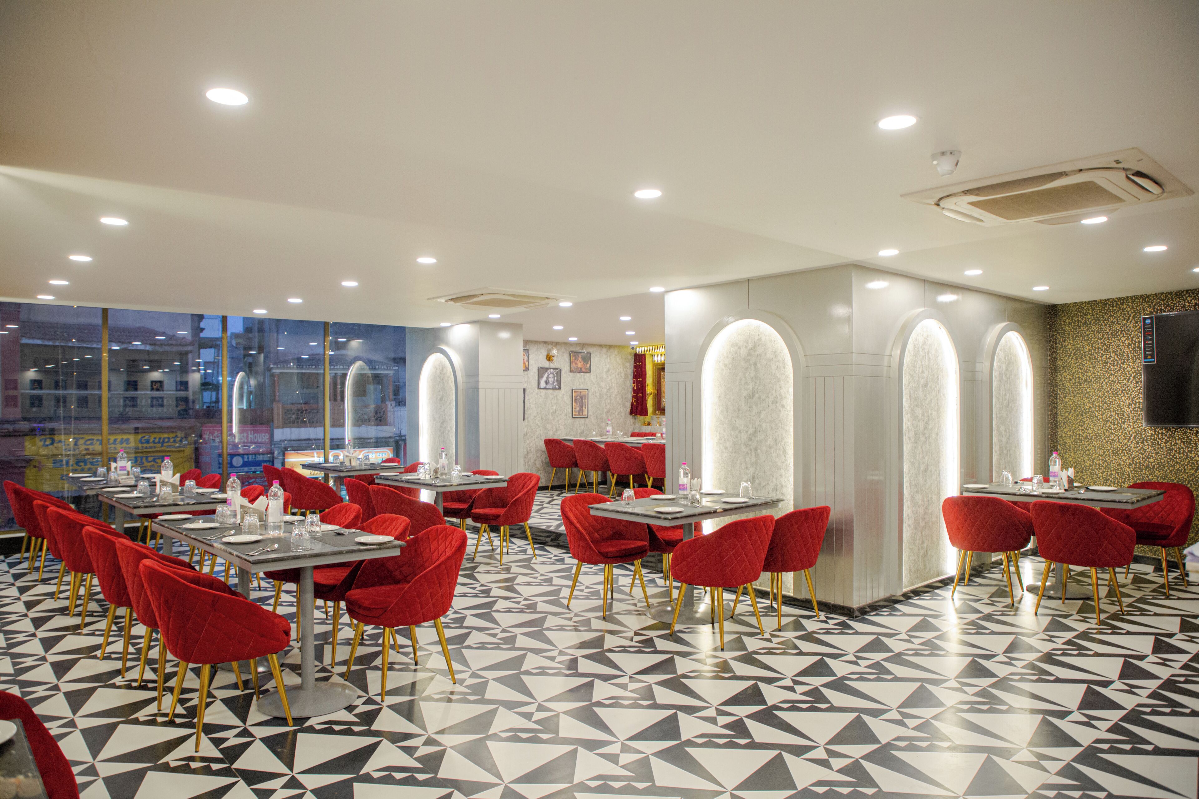 Un restaurante con sillas y mesas rojas, suelo estampado y vistas amplias por grandes ventanales.