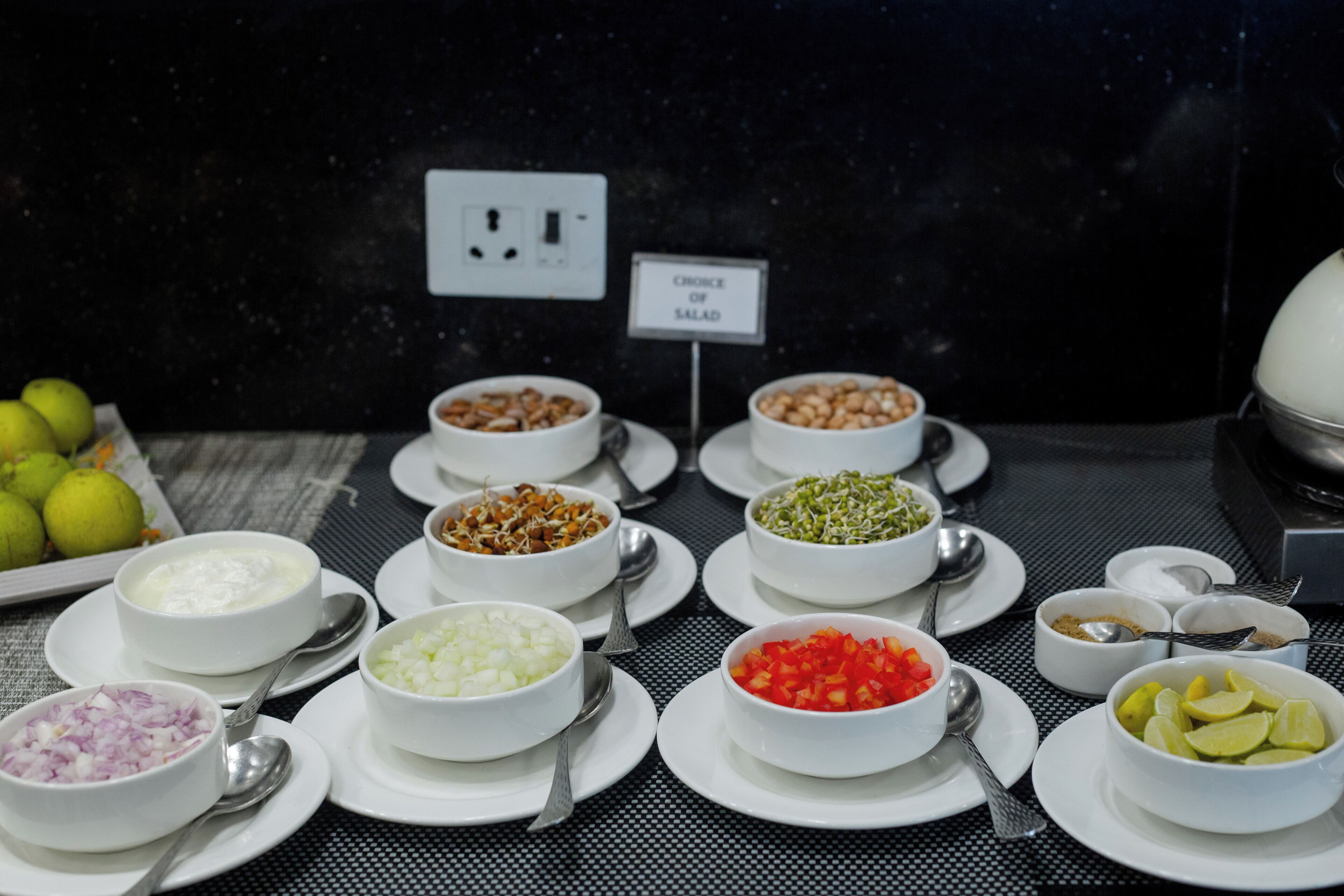 Een buffettafel met diverse gerechten en een bord waarop de salades staan aangegeven.