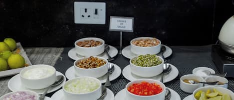 Una mesa de buffet con diversos alimentos y un letrero que indica la opción de ensalada.