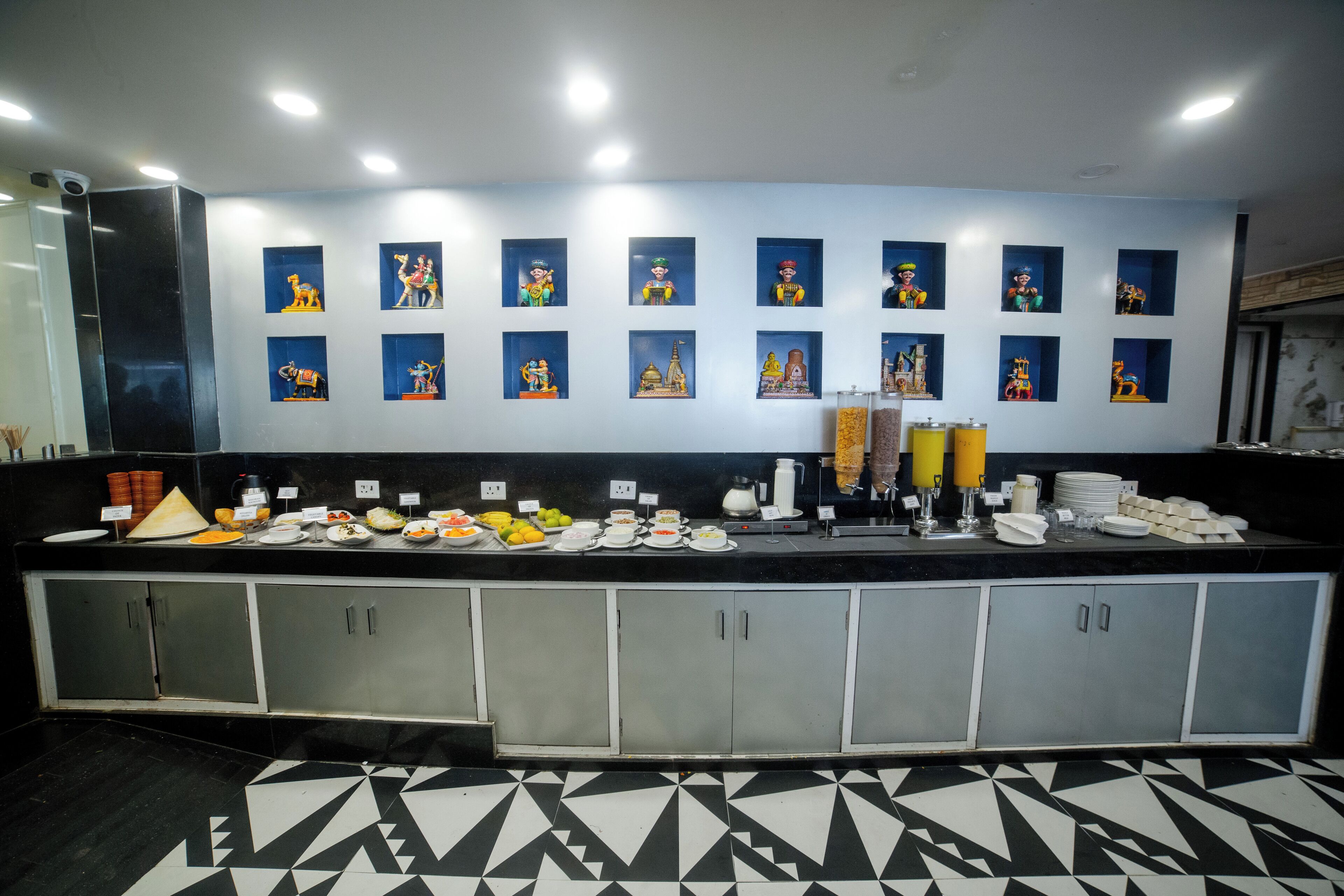 A buffet counter with various food items and a wall decorated with framed pictures.