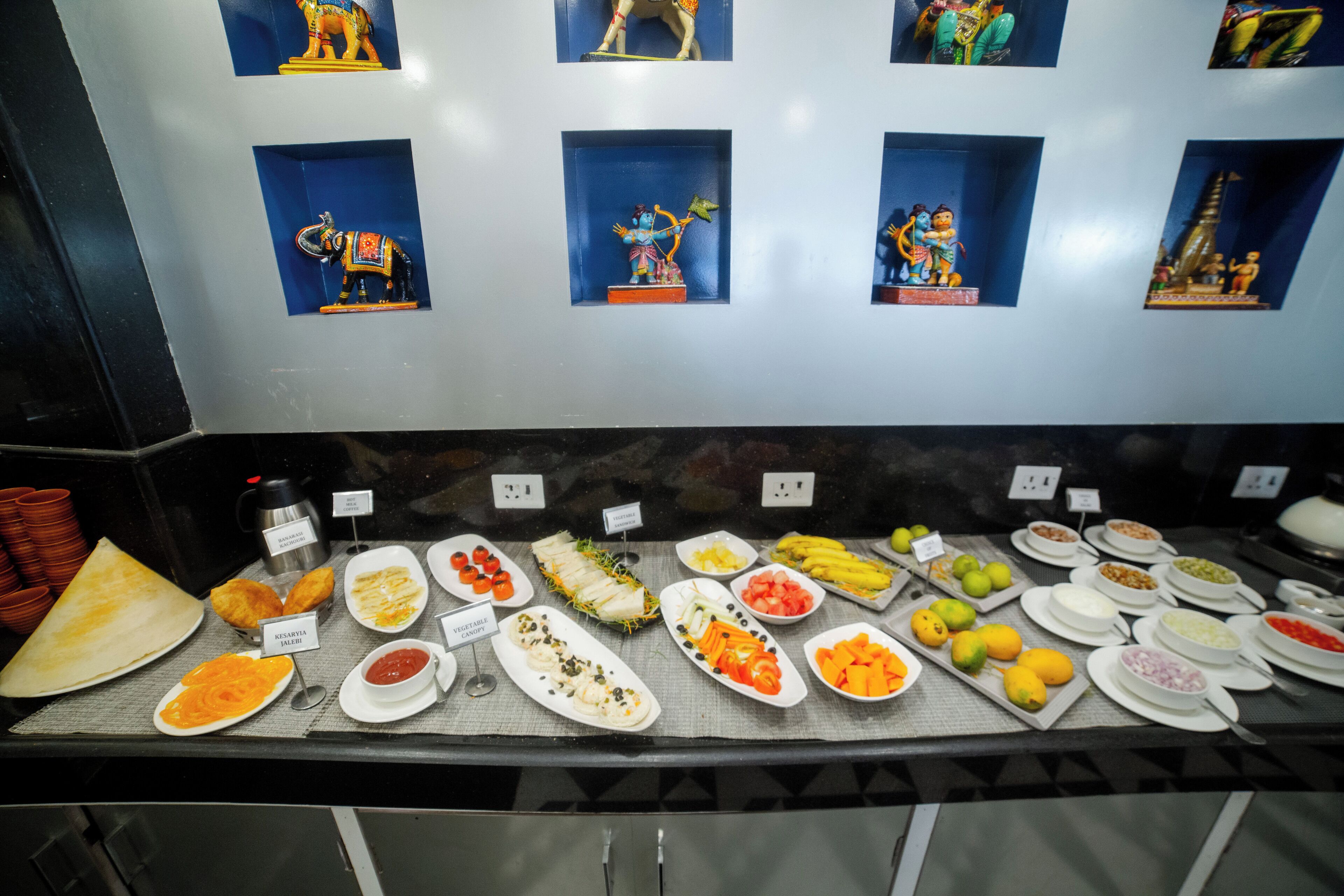 A buffet with various dishes and a wall with small figurines.