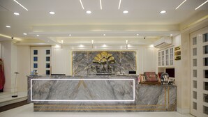 A marble reception desk with a 'PEARL' logo, surrounded by white walls and a tiled floor. - Pearl Courtyard (Varanasi)