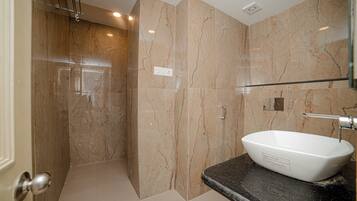 A bathroom with a marble wall, a white sink, and a shower area.