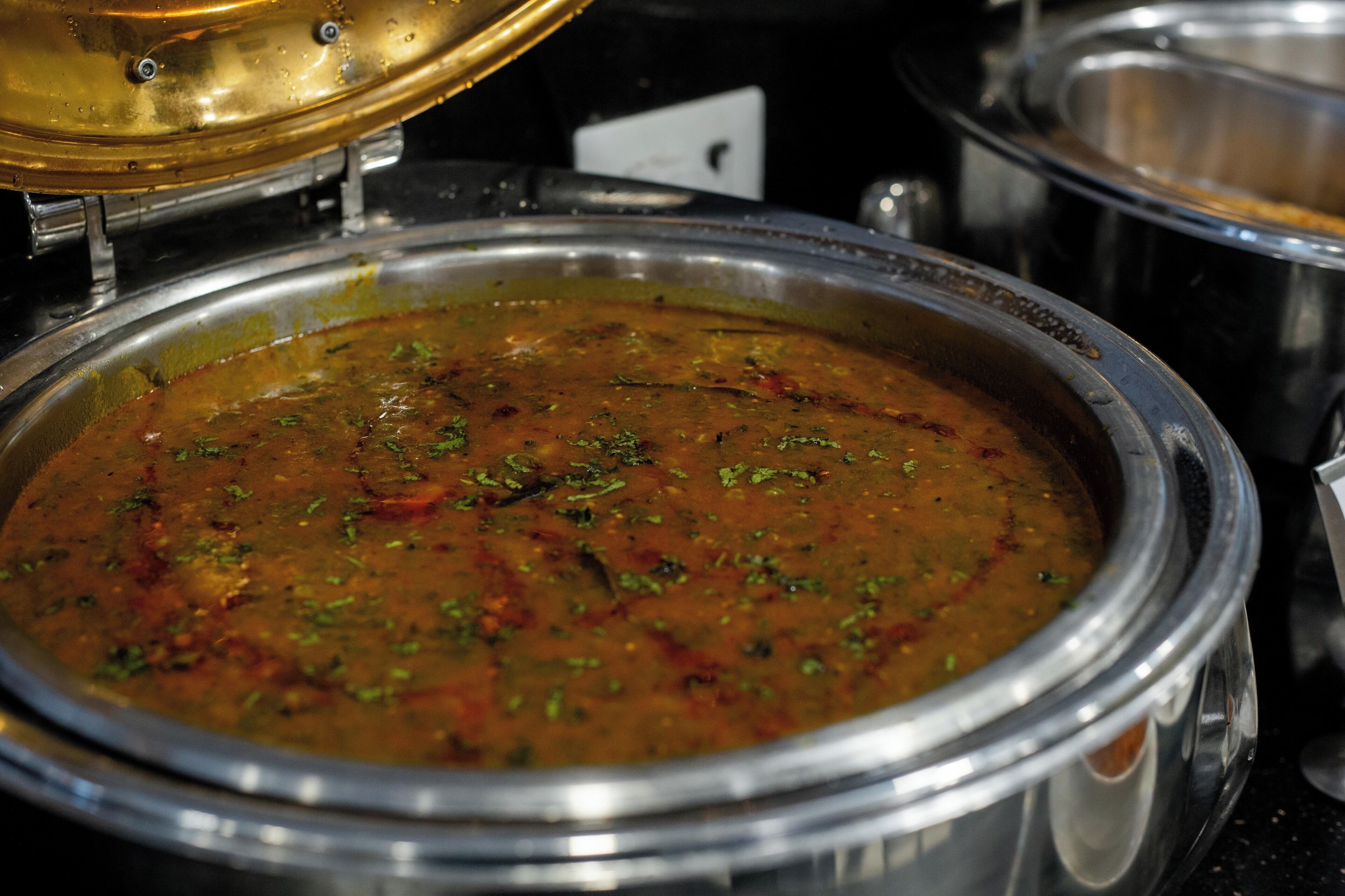 A large metal pot filled with a thick, textured soup or stew, likely served in a restaurant or buffet setting.