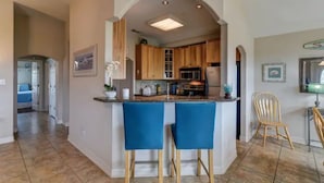 Una cocina con armarios de madera, una isla central con taburetes azules y un cartel que dice 'Beach'.