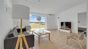 A modern living room with a large window, a flat-screen TV, and a cozy seating area. - 4 bedroom gorgeous home in Løgstrup (Løgstrup)