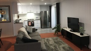 En moderne stue med en grå sofa, et fladskærms-tv og et lille, sort tv-møbel.