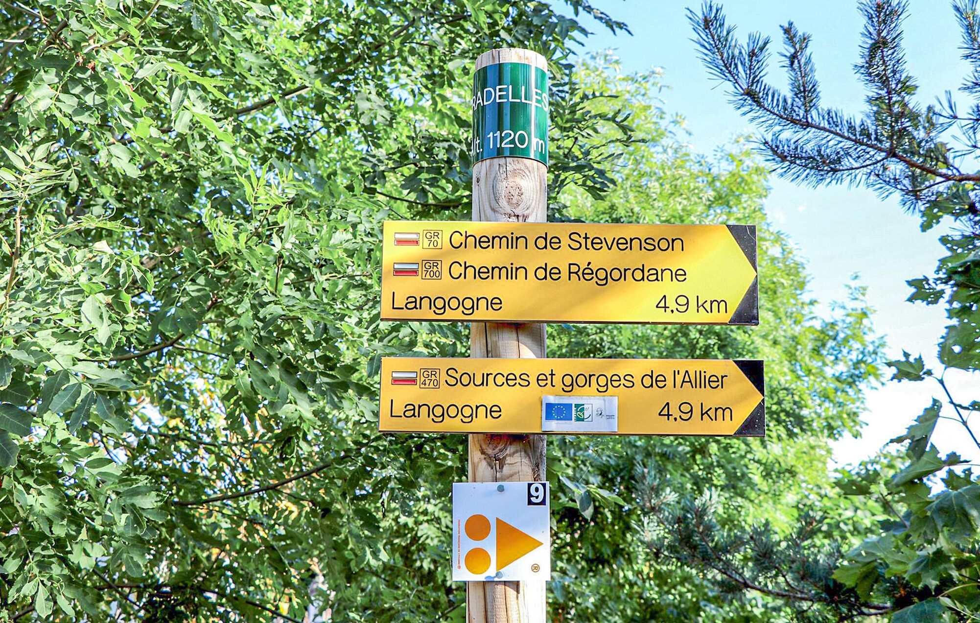 Un cartel con indicaciones y varias flechas que señalan diferentes destinos, incluyendo 'Chemin de Stevenson' y 'Chemin de Régordane', ambos que conducen a Langogne.