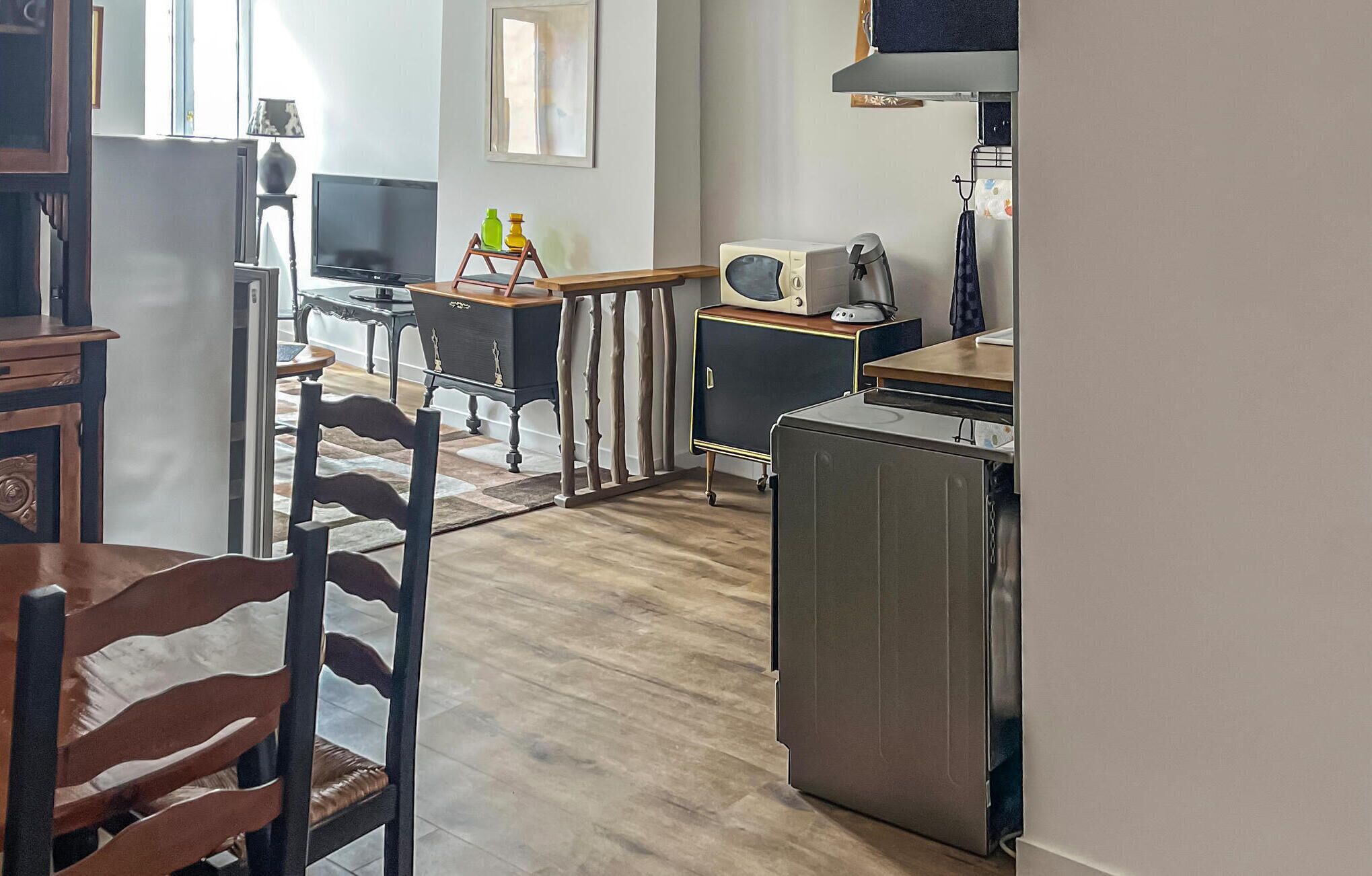 Une cuisine compacte équipée d’un réfrigérateur, d’un four à micro-ondes et d’une cuisinière. Elle comprend également un coin repas avec une chaise et une table.