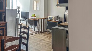 A compact kitchen with a refrigerator, microwave, and stove. There is a dining area with a chair and a table. - Beautiful apartment in Pradelles with WiFi (Pradelles)